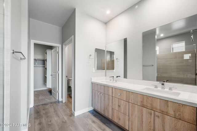 bathroom with wood-type flooring, vanity, toilet, and walk in shower