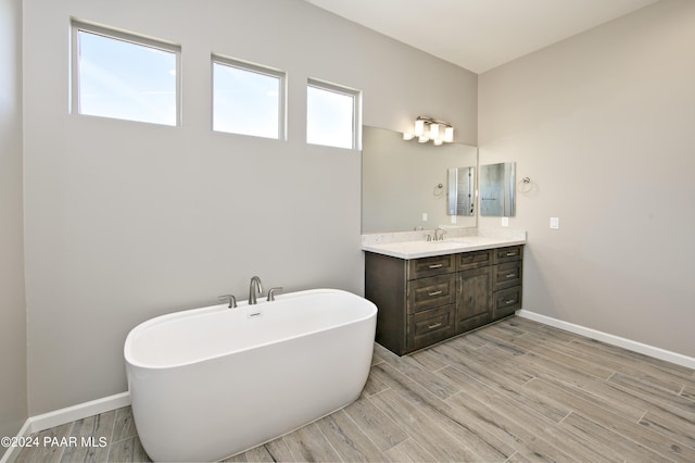 full bathroom featuring baseboards, a freestanding tub, vanity, and wood tiled floor