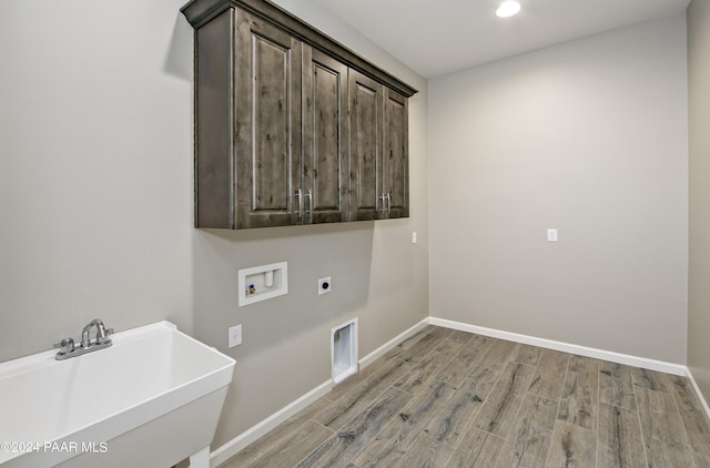 washroom with hookup for a washing machine, a sink, hookup for an electric dryer, cabinet space, and baseboards