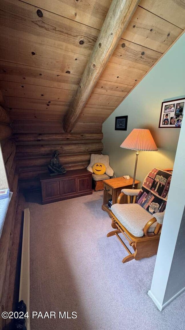 living area featuring log walls, vaulted ceiling with beams, wooden ceiling, and carpet flooring