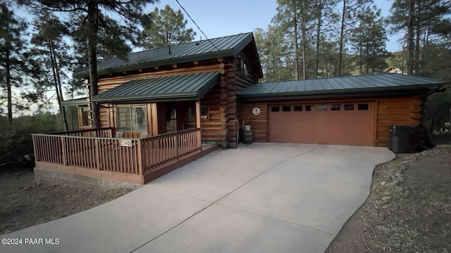 log cabin featuring a porch and a garage