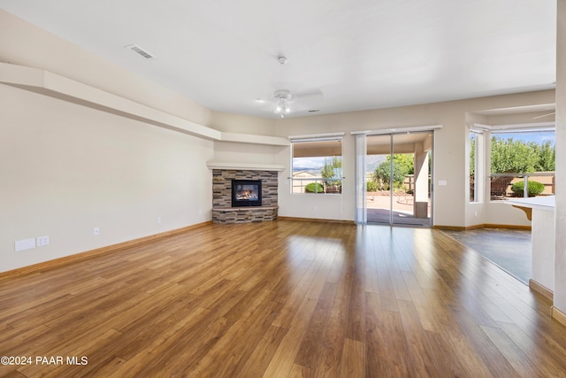 unfurnished living room featuring hardwood / wood-style flooring, ceiling fan, and a fireplace