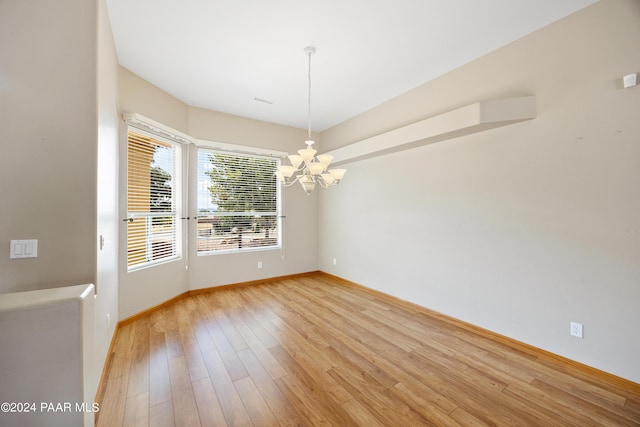 unfurnished room with a chandelier and light wood-type flooring