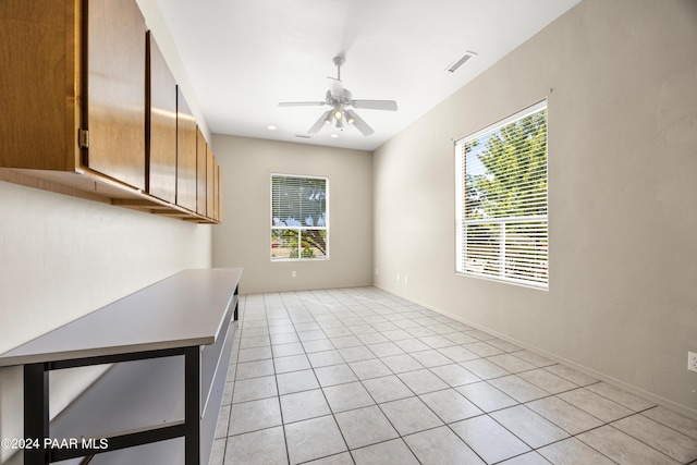 tiled empty room featuring ceiling fan and a healthy amount of sunlight