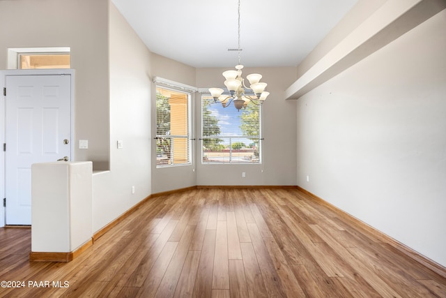 unfurnished dining area featuring hardwood / wood-style flooring and an inviting chandelier