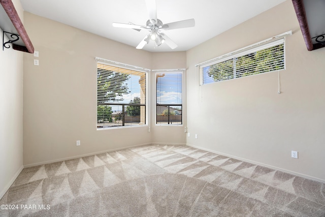 empty room with ceiling fan, a healthy amount of sunlight, and light colored carpet