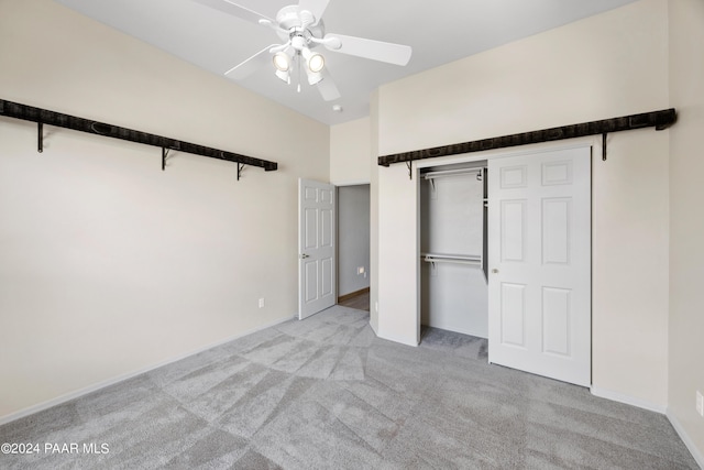 unfurnished bedroom featuring a barn door, ceiling fan, a closet, and light colored carpet