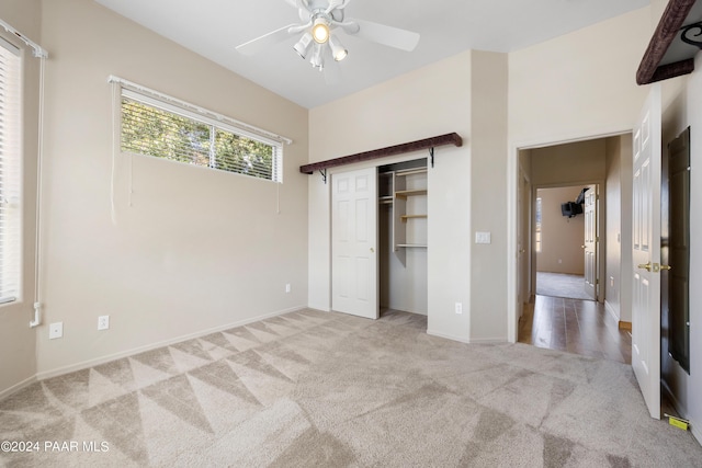 unfurnished bedroom with ceiling fan, light colored carpet, and a closet