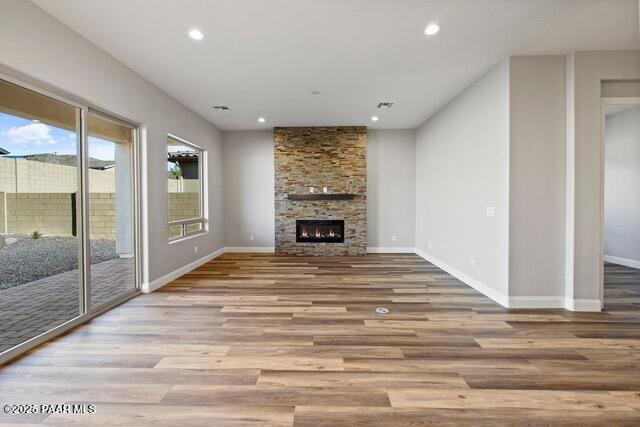 7064 N Robin Nest Ct, Prescott Valley, AZ 86315 - unfurnished living room featuring wood finished floors, recessed lighting, and a stone fireplace