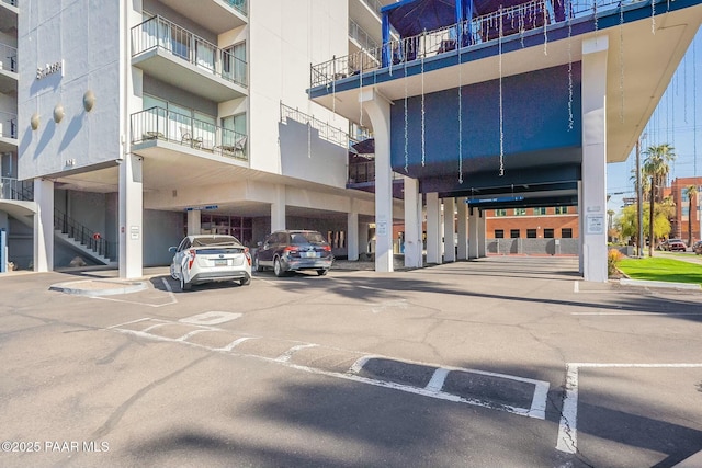view of building exterior with covered and uncovered parking