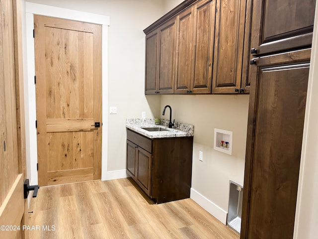 laundry room with hookup for a washing machine, sink, cabinets, and light wood-type flooring