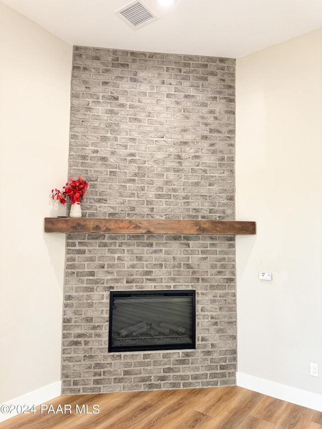 details with a brick fireplace and wood-type flooring