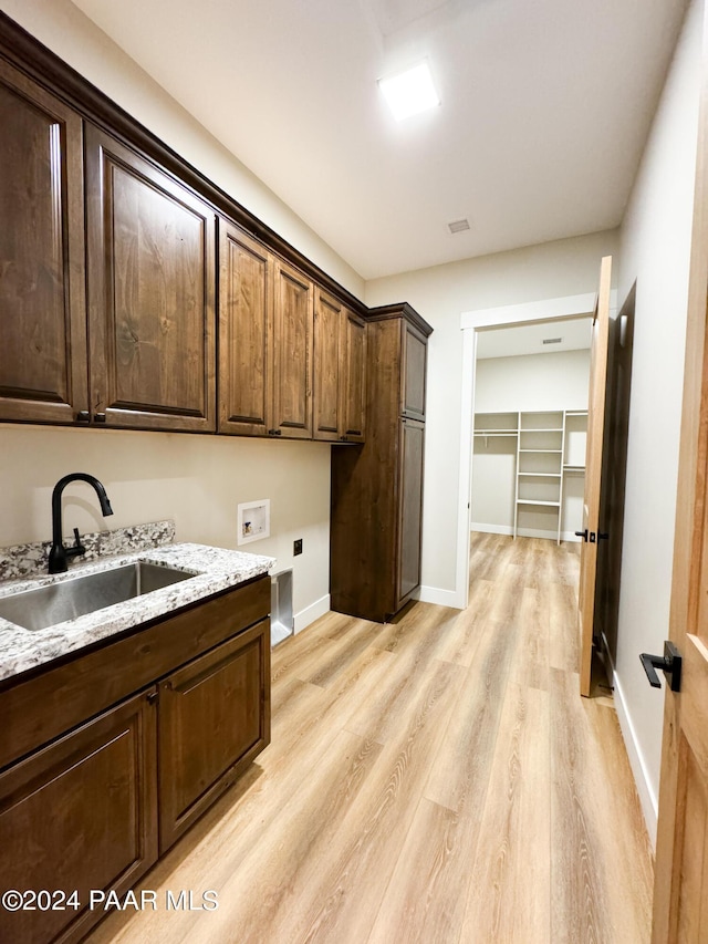 clothes washing area featuring sink, cabinets, light wood-type flooring, washer hookup, and hookup for an electric dryer