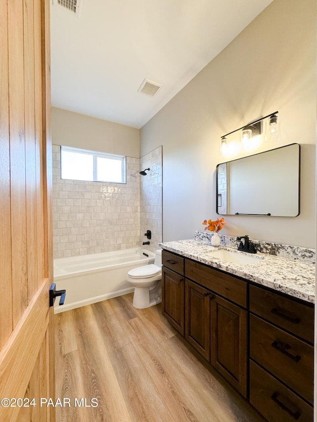 full bathroom featuring vanity, hardwood / wood-style flooring, toilet, and tiled shower / bath