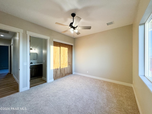 unfurnished bedroom featuring carpet, connected bathroom, and ceiling fan