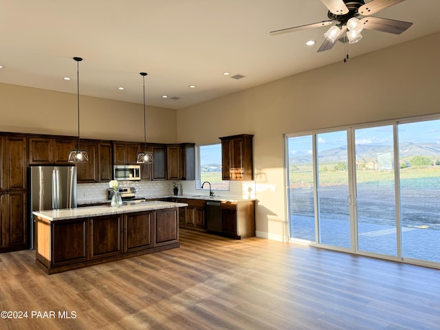 kitchen featuring a kitchen island, decorative light fixtures, dark brown cabinetry, stainless steel appliances, and a mountain view