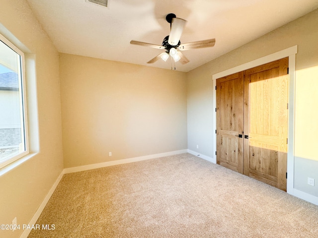 unfurnished bedroom with multiple windows, carpet, and ceiling fan