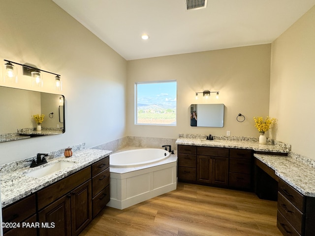 bathroom with wood-type flooring, a bathing tub, and vanity