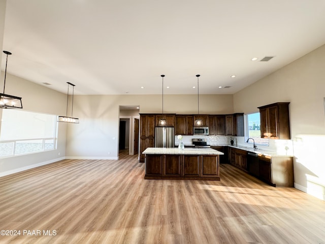 kitchen with pendant lighting, stainless steel appliances, a center island, and sink