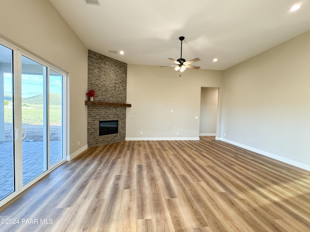 unfurnished living room featuring a brick fireplace, light hardwood / wood-style floors, and ceiling fan