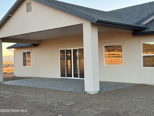 back house at dusk featuring a patio area