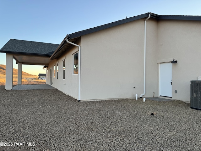 property exterior at dusk featuring central AC unit and a patio area