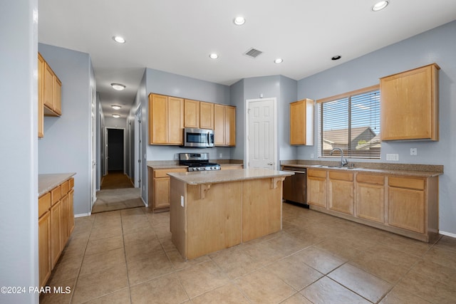 kitchen featuring visible vents, a breakfast bar area, appliances with stainless steel finishes, a center island, and a sink