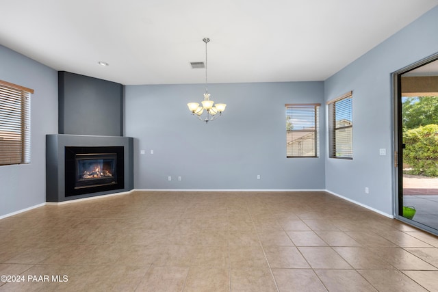 unfurnished living room with baseboards, a glass covered fireplace, visible vents, and a healthy amount of sunlight