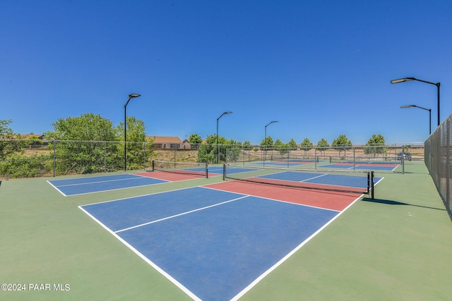 view of tennis court featuring community basketball court and fence