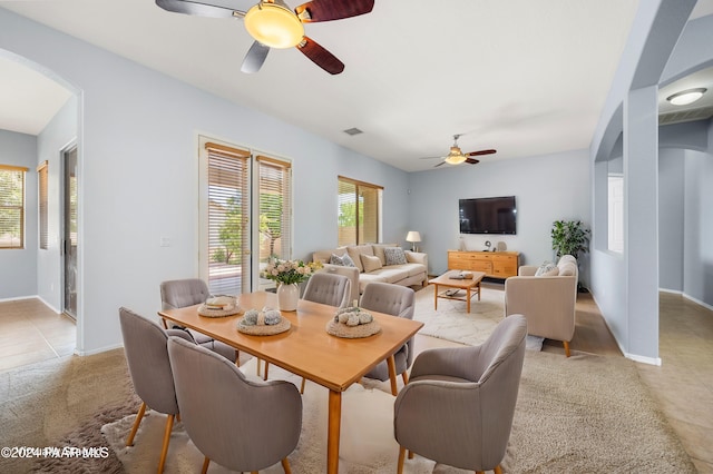 dining room featuring arched walkways, ceiling fan, light tile patterned floors, visible vents, and baseboards