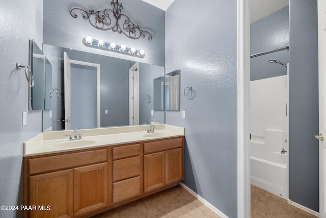 bathroom featuring double vanity, shower / bathing tub combination, tile patterned flooring, and a sink