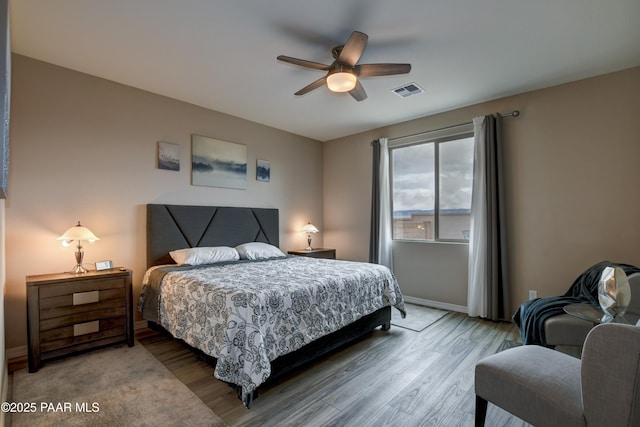 bedroom with visible vents, ceiling fan, baseboards, and wood finished floors