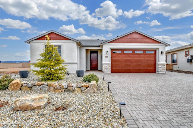 view of front facade featuring stone siding, stucco siding, an attached garage, and decorative driveway