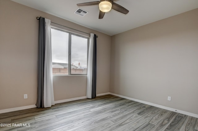 spare room with ceiling fan, light wood-style floors, visible vents, and baseboards