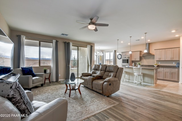 living area featuring recessed lighting, visible vents, light wood-style flooring, and ceiling fan with notable chandelier