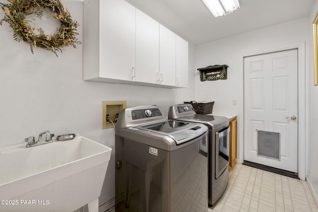 washroom featuring washing machine and clothes dryer, a sink, cabinet space, and light floors