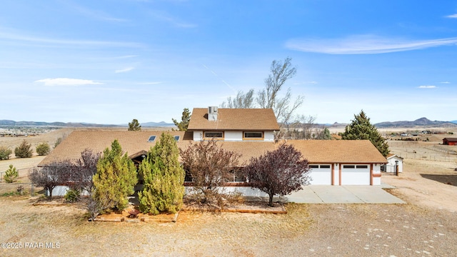 view of front of property with driveway, an attached garage, and a mountain view
