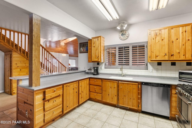 kitchen featuring light tile patterned floors, a sink, stainless steel appliances, and a peninsula