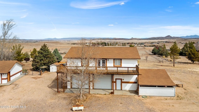 view of front of house with an outdoor structure, a mountain view, and fence