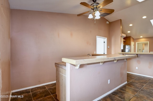 9100 E Lonesome Valley Rd, Prescott Valley, AZ 86315 - kitchen with vaulted ceiling with skylight, a breakfast bar area, a ceiling fan, and baseboards