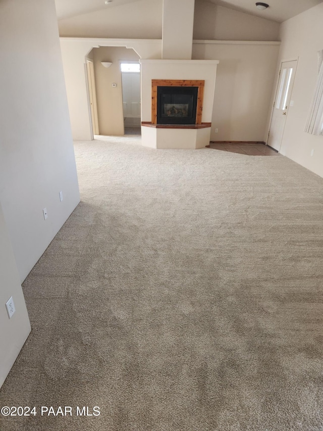 unfurnished living room with light colored carpet and vaulted ceiling