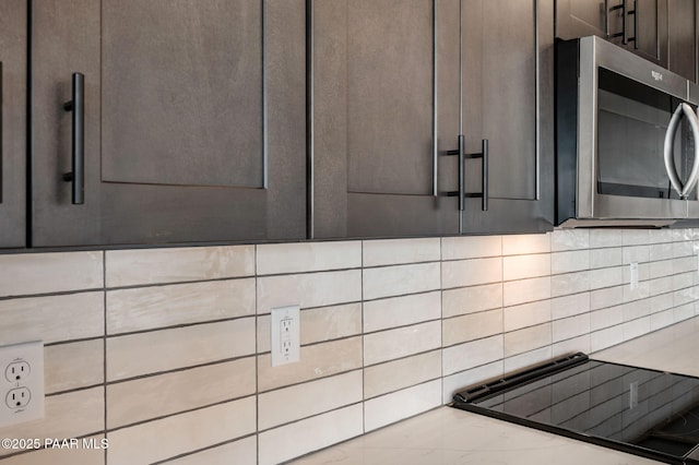 details featuring dark brown cabinets, backsplash, and light stone counters