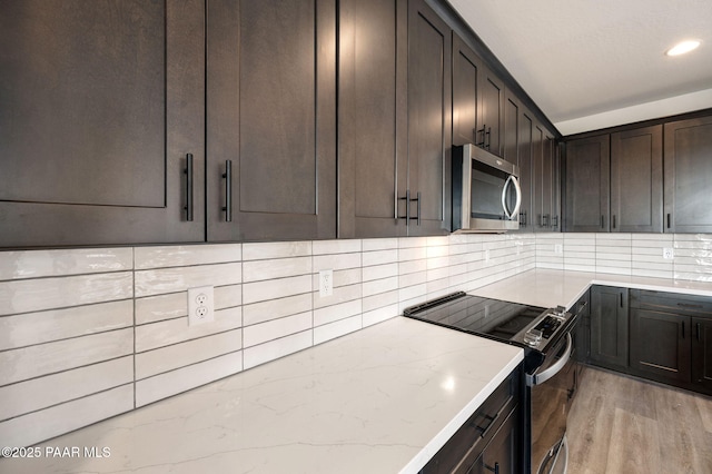 kitchen featuring light stone countertops, appliances with stainless steel finishes, dark brown cabinetry, and light hardwood / wood-style flooring