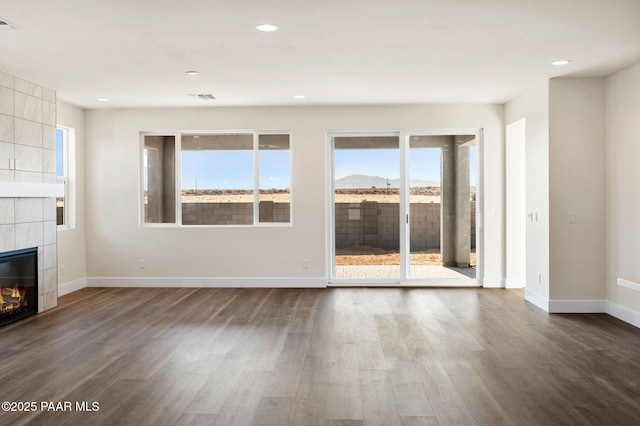 unfurnished living room with plenty of natural light, dark hardwood / wood-style flooring, and a fireplace