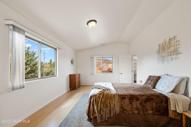 bedroom with lofted ceiling, wood finished floors, and baseboards