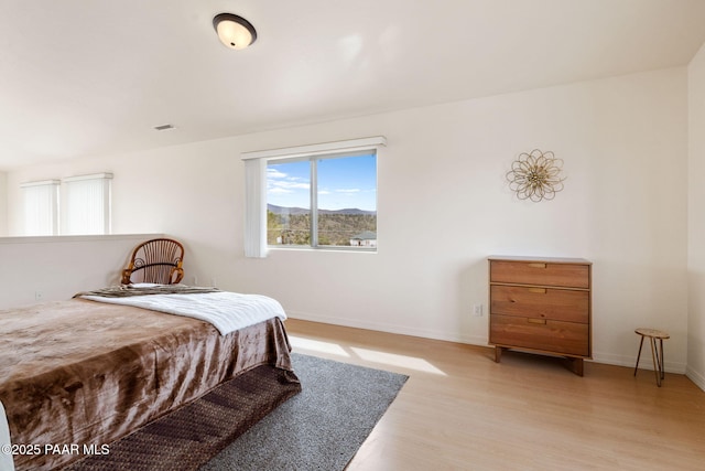 bedroom with light wood finished floors, visible vents, and baseboards