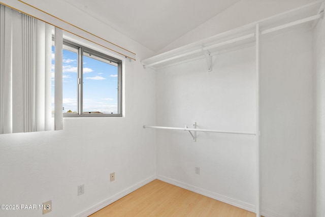 spacious closet with light wood-style flooring and vaulted ceiling