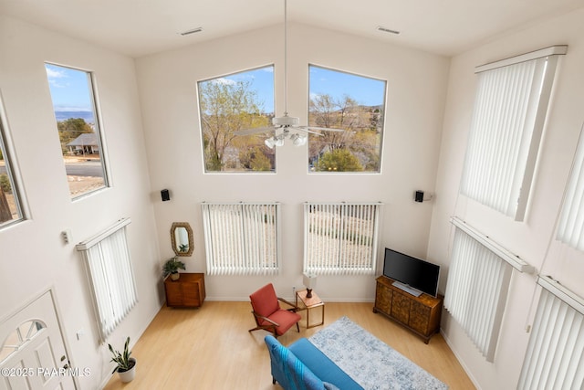 living area with visible vents, a high ceiling, wood finished floors, and a ceiling fan