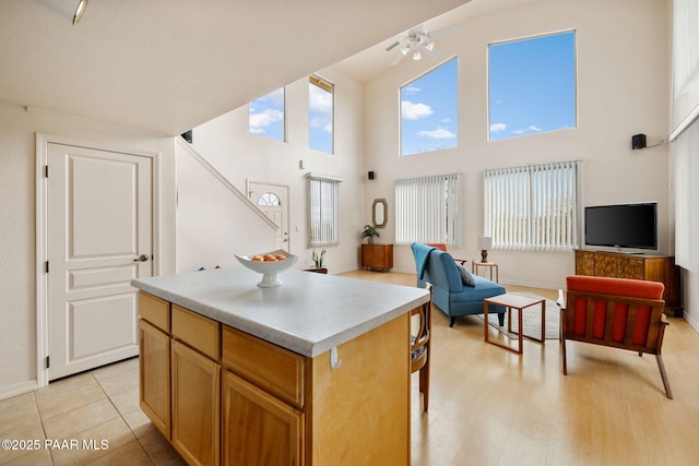 kitchen featuring a ceiling fan, baseboards, light countertops, open floor plan, and a center island