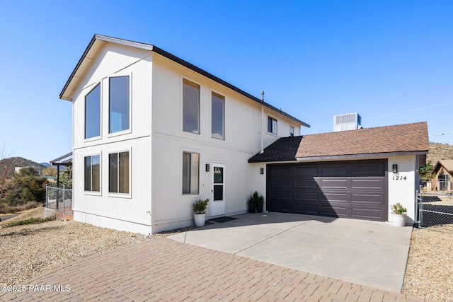 view of front facade featuring fence, a garage, driveway, and roof with shingles